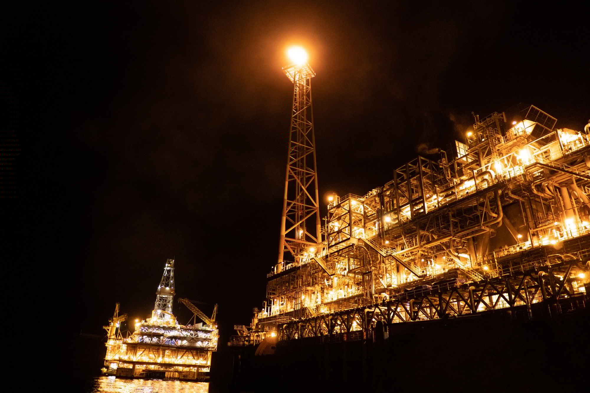 FPSO tanker vessel near Oil platform Rig at night. Offshore oil and gas industry